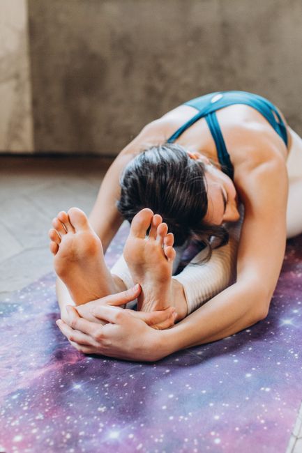 A woman performs Paschimottanasana yoga pose indoors, promoting relaxation and mindfulness.