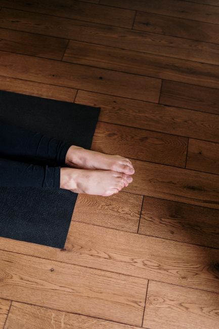 Feet resting on a yoga mat indoors with wooden flooring emphasizes wellness and mindfulness.