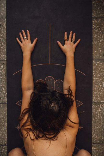 Woman practicing calming yoga pose on a detailed mat indoors.