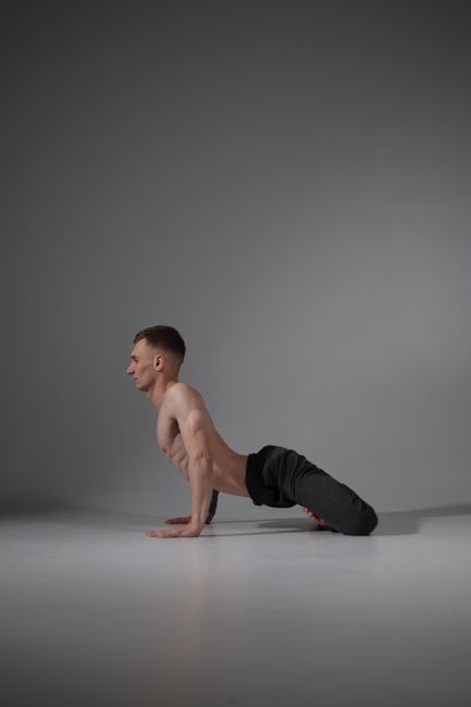 Side view of a man performing yoga in a studio, highlighting physical fitness and concentration.