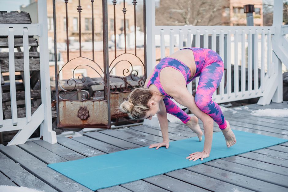 Full body of barefoot concentrated young female practicing yoga in Kakasana position on mat outdoors