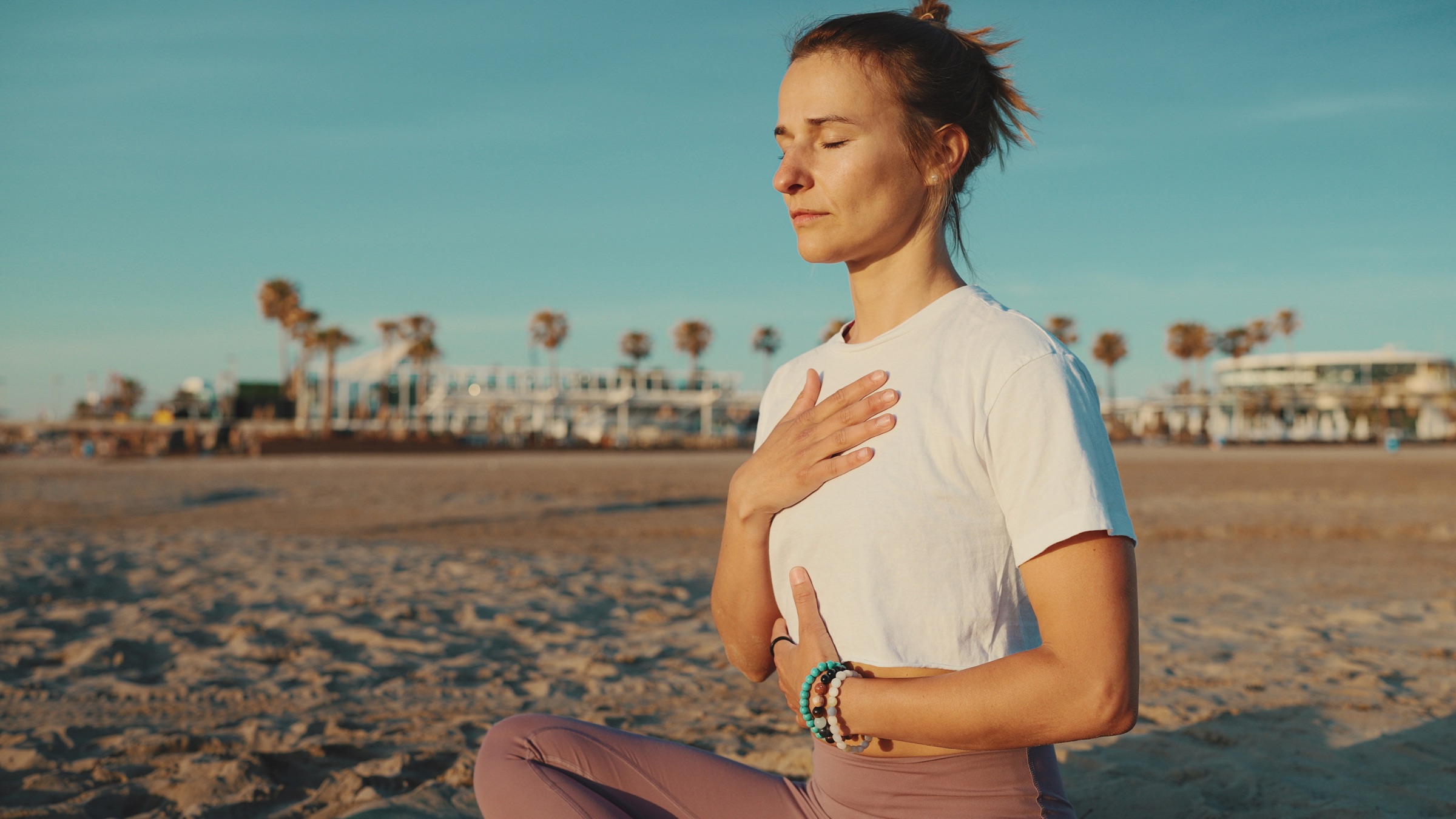 Woman breathing with a hand on her chest on a beach at sunrise