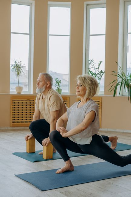 Senior couple engaged in yoga with blocks indoors, enhancing flexibility and wellness.