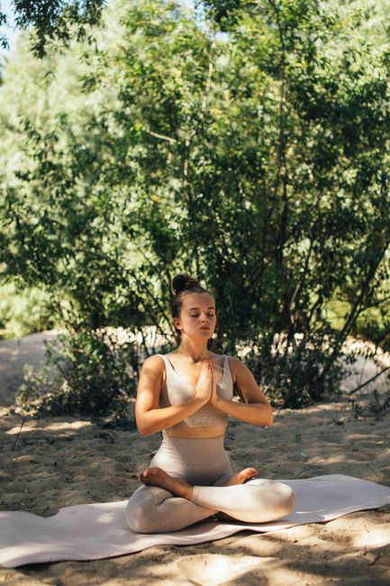 A woman practicing yoga meditation in peaceful outdoor nature setting.