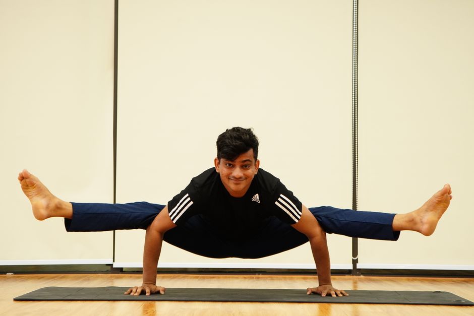 Firefly Pose: Adult man practicing an advanced yoga pose on a mat indoors, showcasing balance and strength.
