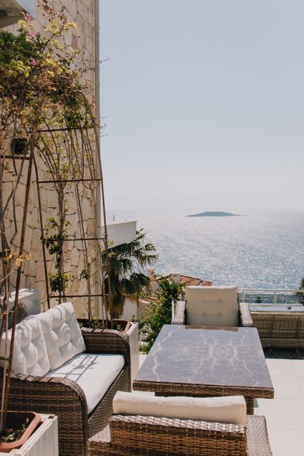 Beautiful terrace with comfy furniture overlooking the sparkling sea under a sunny sky.