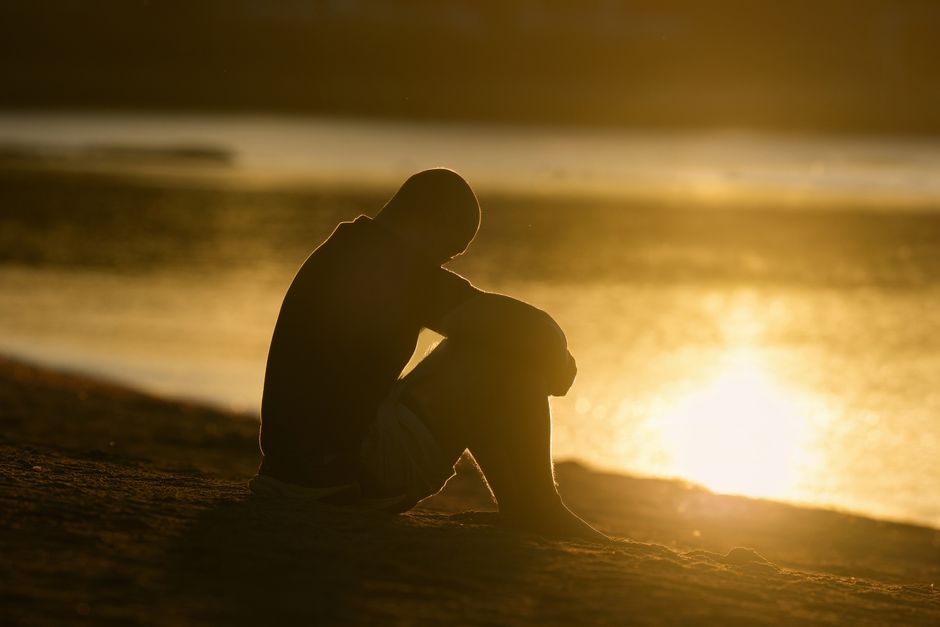 Silhouette of a person meditating by the water as the sun rises at Cove Island Park in Stamford, Connecticut.