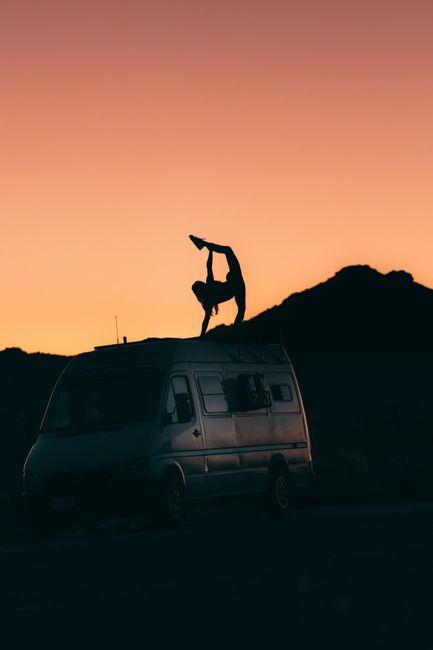 A person in a yoga pose on a van during sunset in Joshua Tree, California.