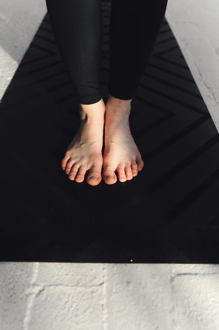 Close-up image of feet on a black yoga mat indoors. Ideal for fitness and wellness concepts.