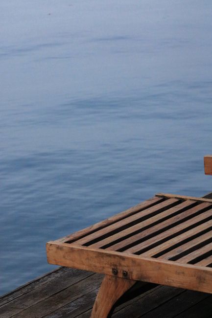 A serene view of a wooden sunbed on a promenade with the tranquil sea in Selimiye, Türkiye.