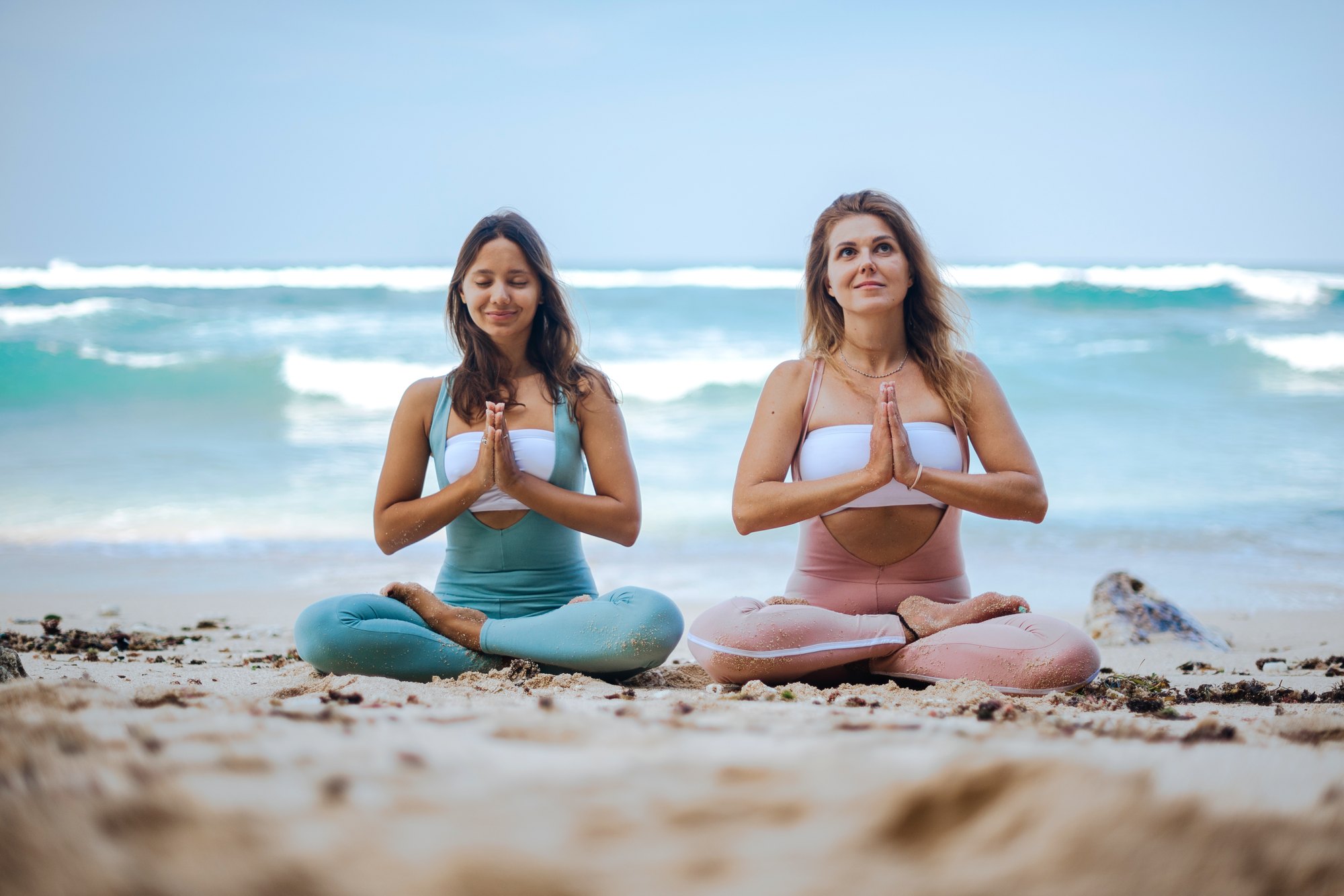 Two women in namaste on a beach