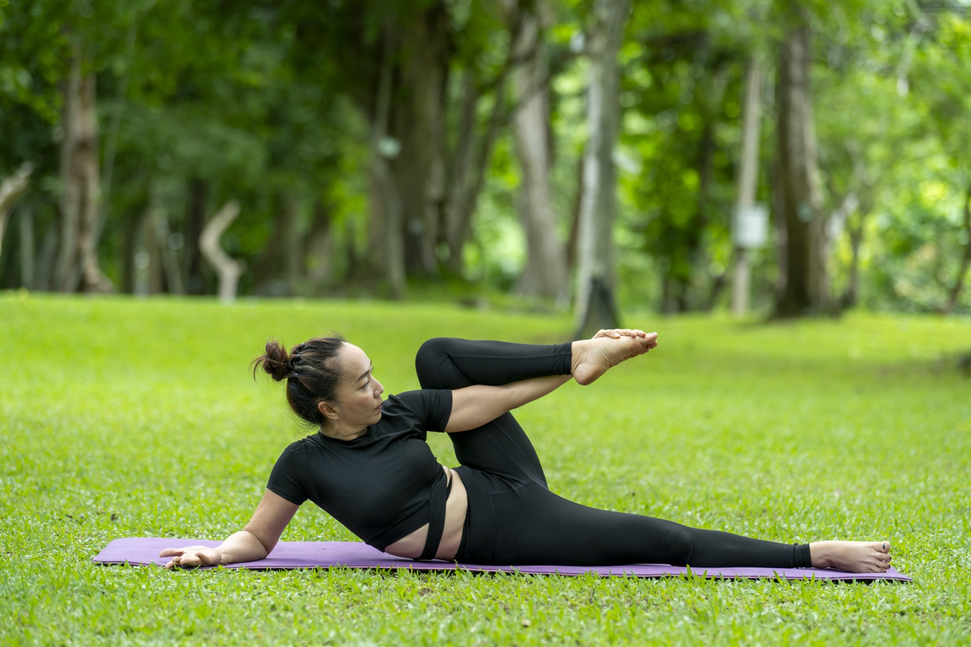Reclining spinal twist on a mat in a park