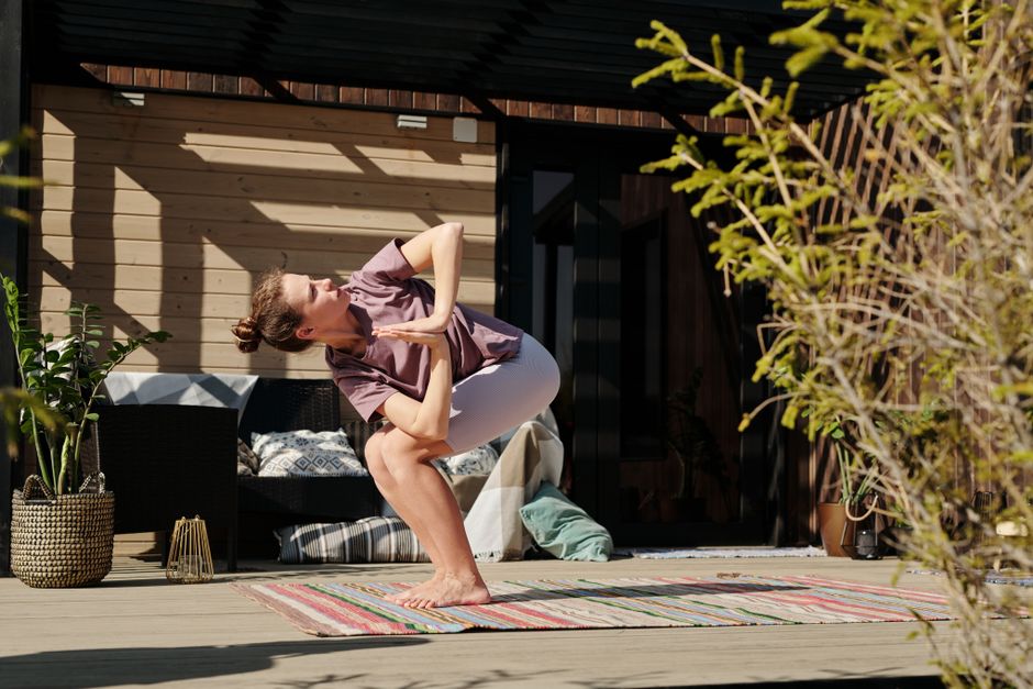 Adult woman performing a yoga pose on a sunny deck, embracing a healthy lifestyle.