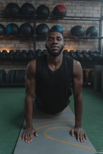 African American man doing yoga upward facing dog pose in gym for wellness.