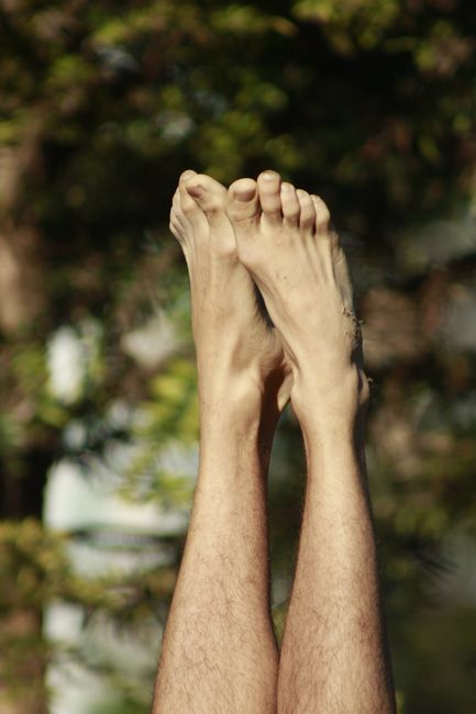 Close-up of bare feet and legs lifted against a blurred natural backdrop, suggesting relaxation and freedom.