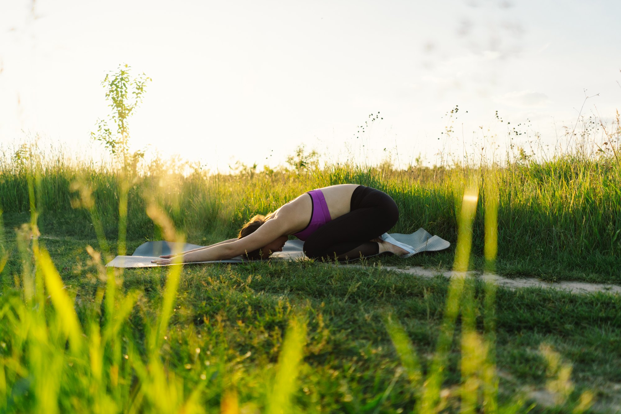 Child's pose in tall grass at golden hour