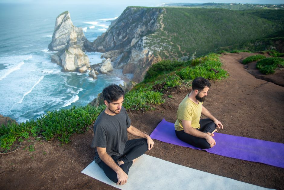 Two men meditating on a scenic cliffside in Portugal. Serenity and nature combined.