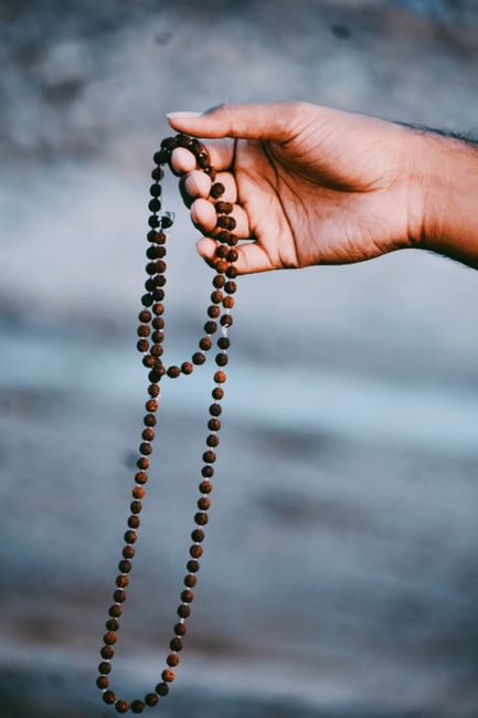 Close-up of a hand holding a Rudraksha bead necklace, symbolizing spirituality and meditation.