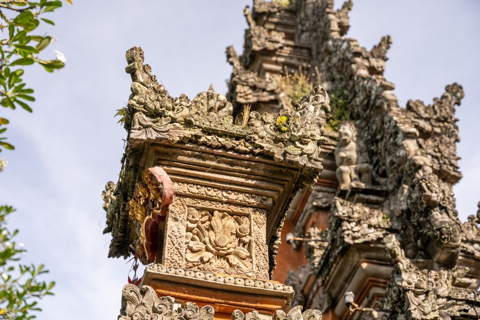 Close-up view of intricate carvings on a traditional Balinese temple under a clear sky.
