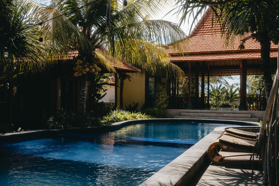 Relax by a luxurious tropical pool surrounded by lush palm trees under a sunny sky, perfect for summer getaways.