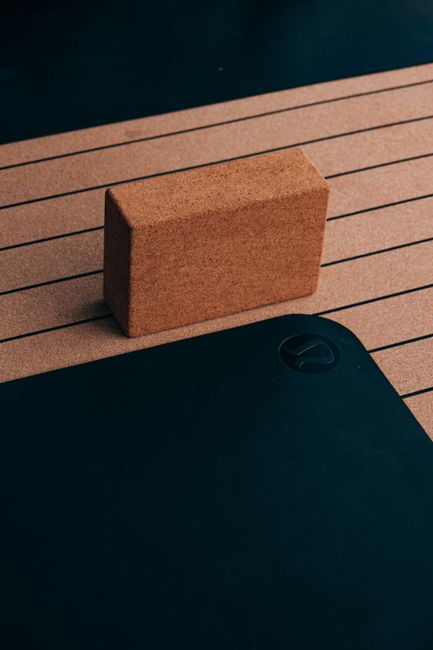 Close-up of a cork yoga block and striped yoga mat, essential for fitness routines.